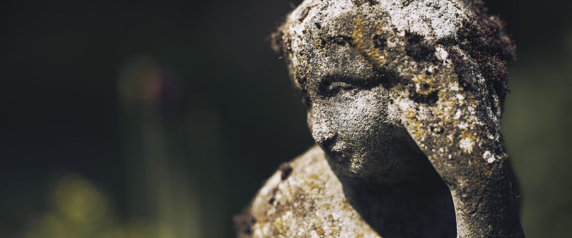 A closeup shot of a rust mossy stone statue of a female on blurred background